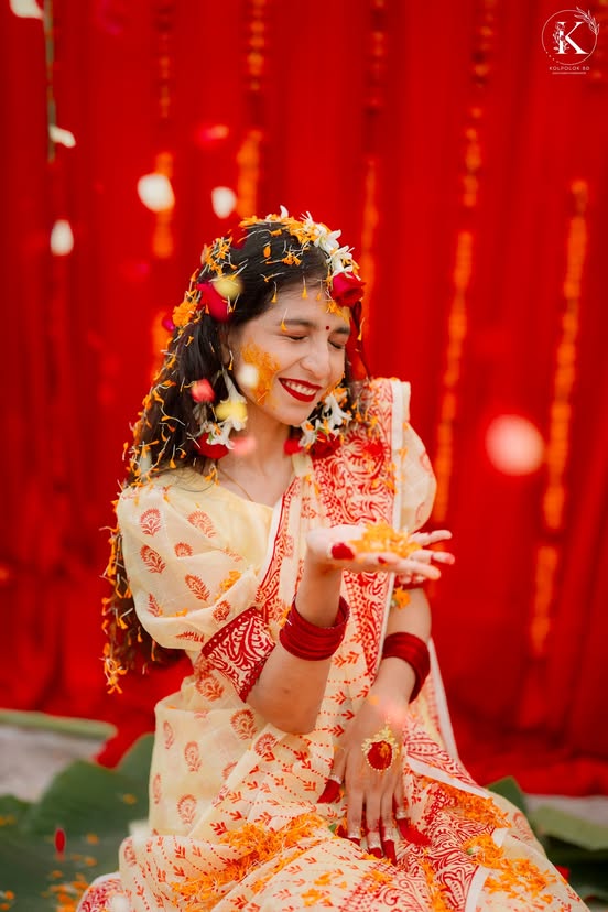 Joyful bride surrounded by flower petals at holud
